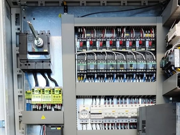 Quadro elettrico aperto con file di contattori, interruttori e cablaggi ordinati nelle canaline