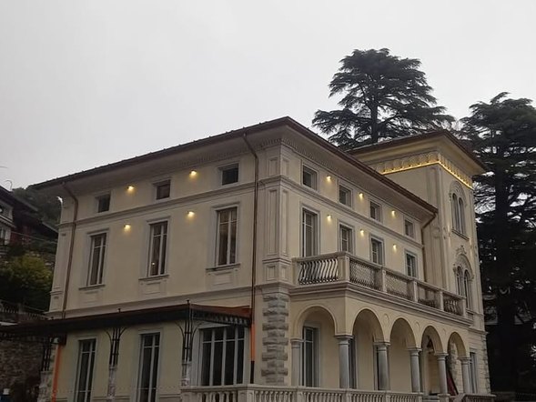 Facciata di una villa d'epoca con faretti accesi sotto le finestre e lungo il cornicione