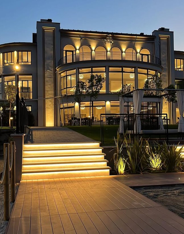 Edificio con grandi vetrate illuminate e gradini con luci a LED lungo il percorso d'ingresso